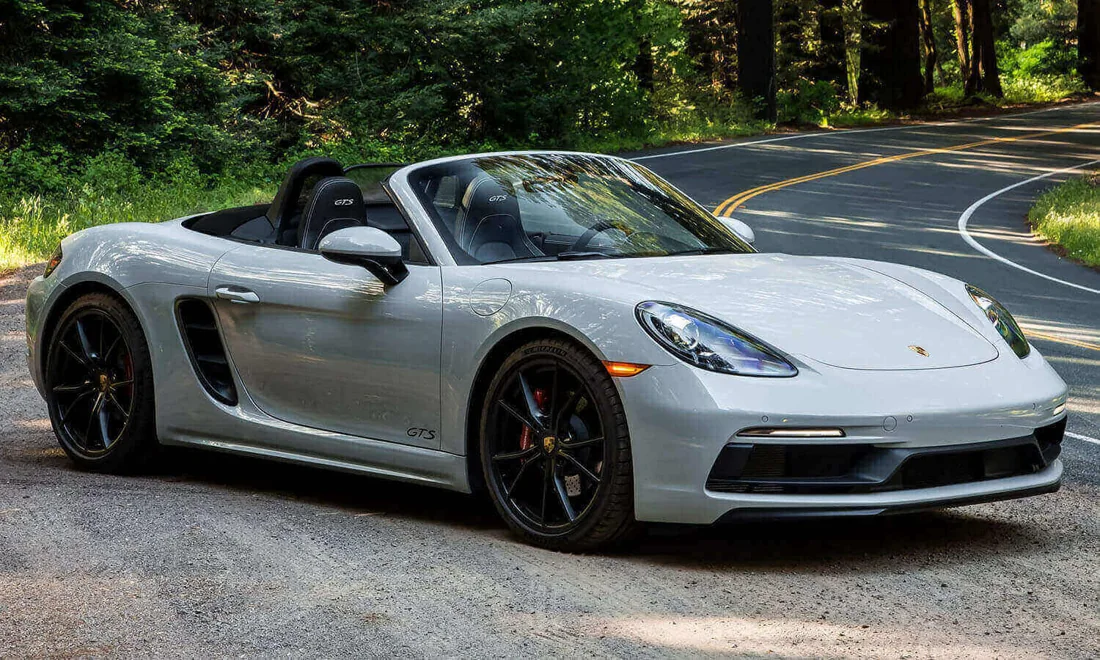 Silver Porsche Boxster GTS on a tree-lined road
